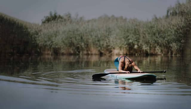 Woman Practicing Yoga On Paddle Board