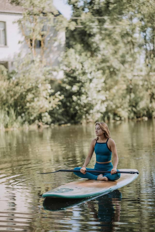 Woman Sitting on Paddle Board in Calm River