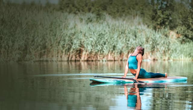 Woman Practicing Yoga On Paddle Board