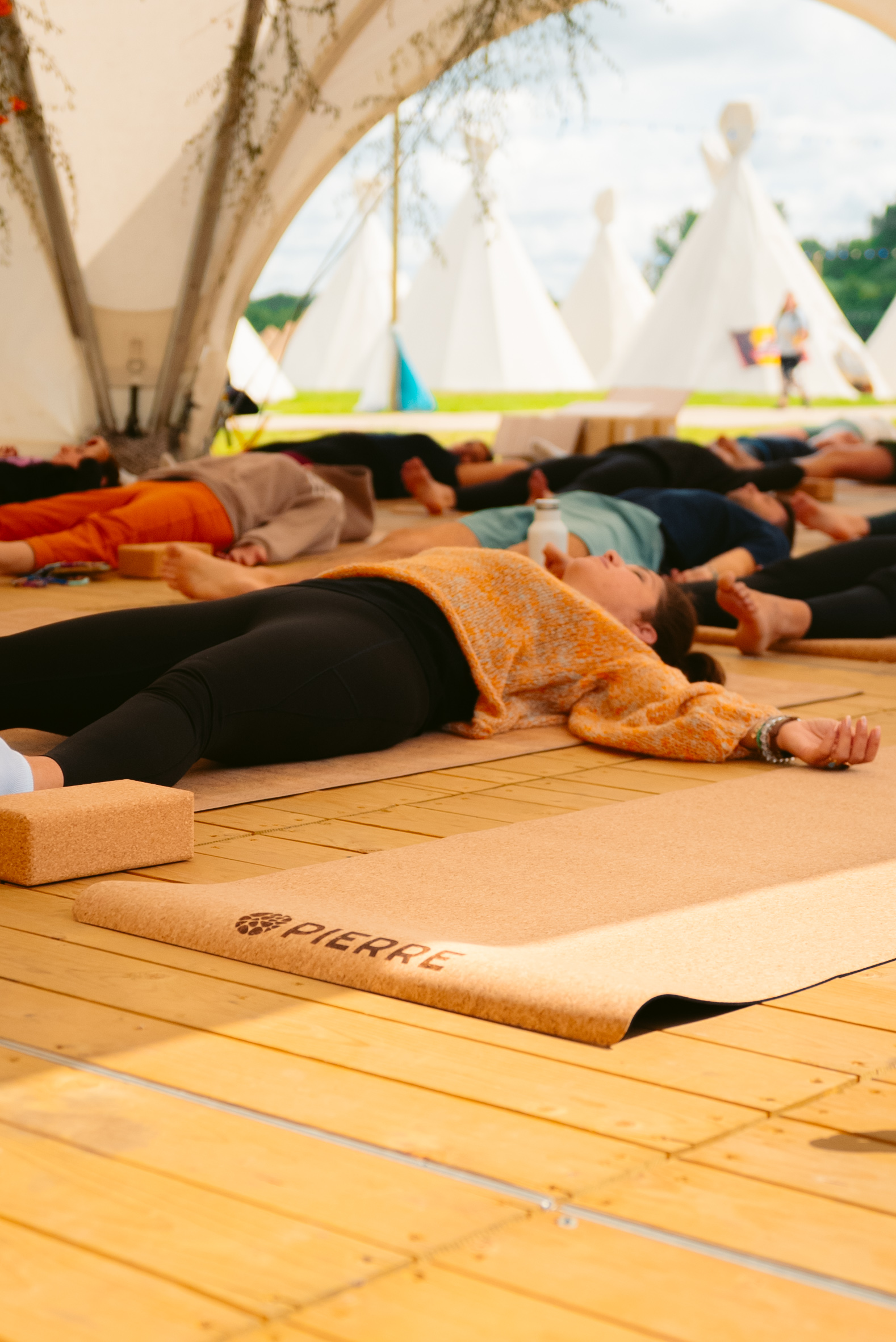 Festival yoga class resting in savasana beside a tipi