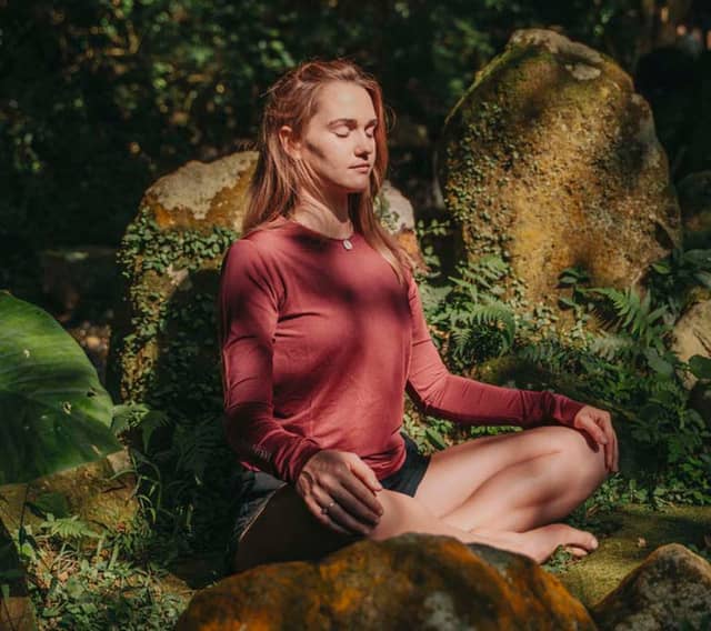 Woman Meditating In Nature Near Rocks