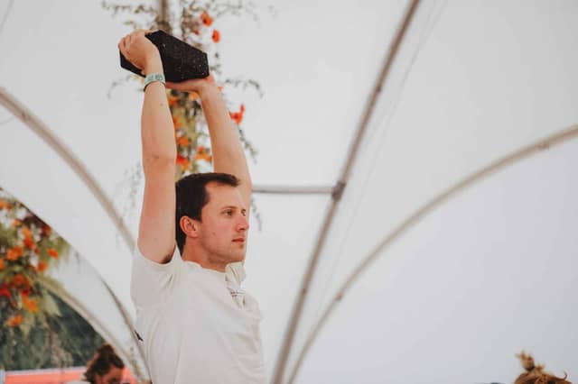 Man Holding Black Yoga Block Overhead