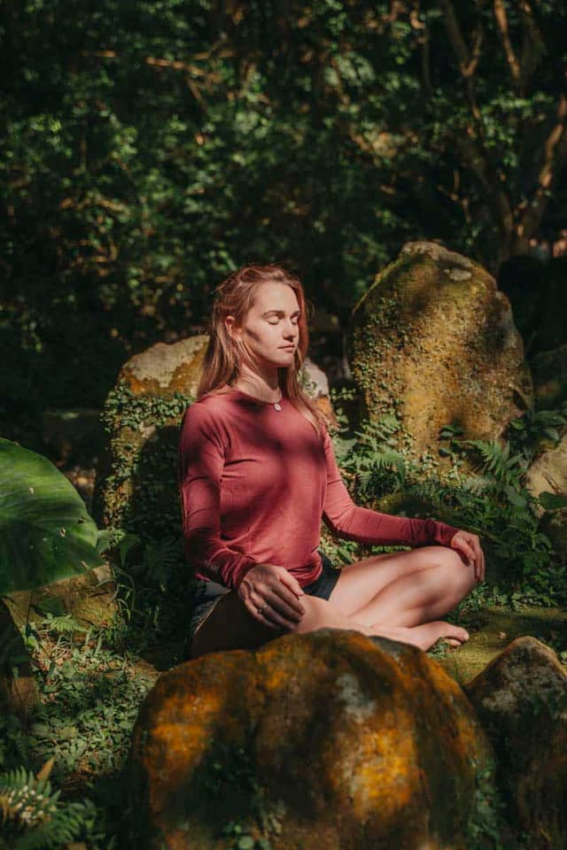 Woman Meditating Outdoors In Lush Garden
