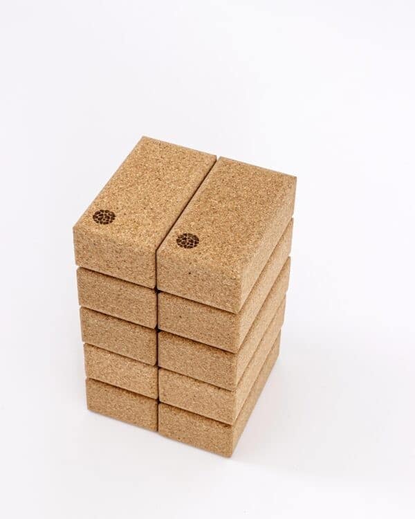 A tall vertical stack of sustainable cork yoga blocks featuring the Pierre Sports circular logo on a white background.