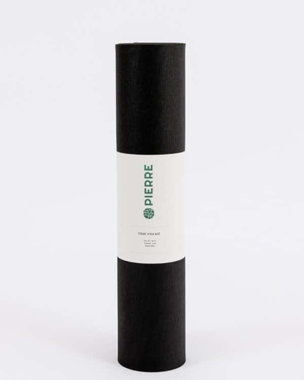 A rolled Pierre Sports black 'Crow' yoga mat with a white branded paper sleeve on a plain white background.