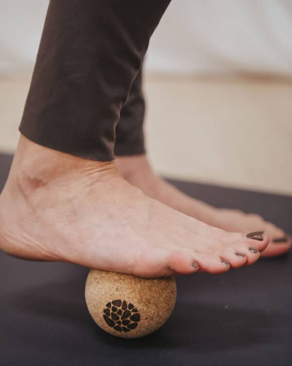 Close up of a person's foot rolling on a Pierre Sports sustainable cork massage ball for myofascial release.